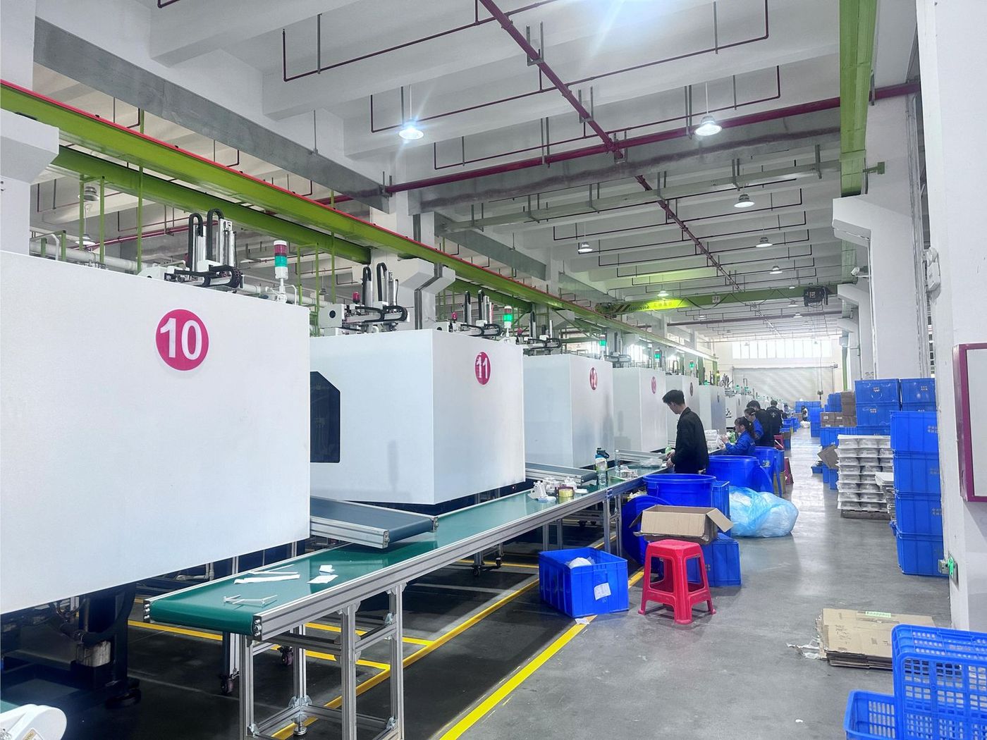 Operators assembling and packing parts at conveyor lines beside the numbered presses