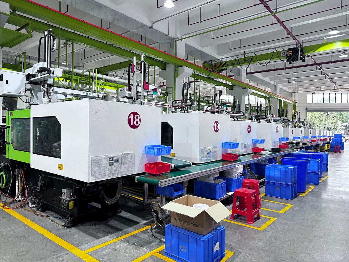 Long row of numbered injection presses with robotic take-off and conveyors, crates staged at each station
