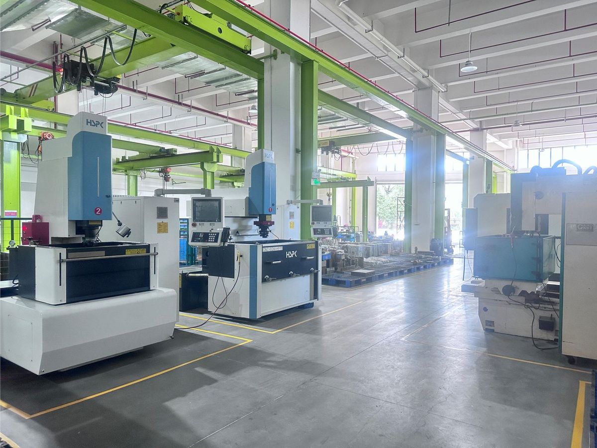 EDM bay: numbered CNC die-sinking EDM machines under jib cranes, with mould plates staged behind