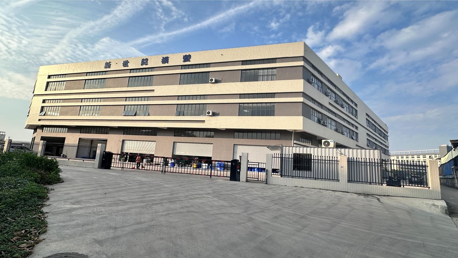 New Century Mould & Plastic in Shunde: a four-storey factory building with gated forecourt and roller-door loading bays