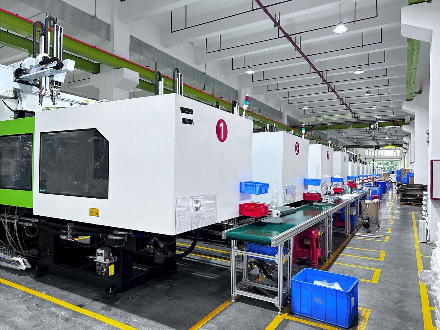 Numbered injection moulding machines with robotic take-off arms feeding conveyors in the moulding hall
