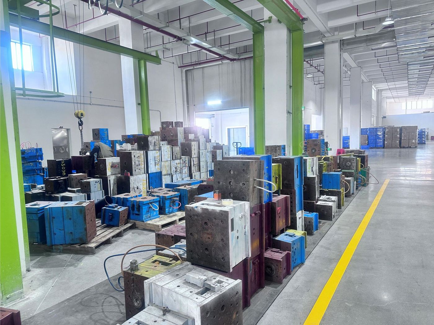 On-site mould library: rows of numbered injection mould bases staged on pallets beside the warehouse aisle