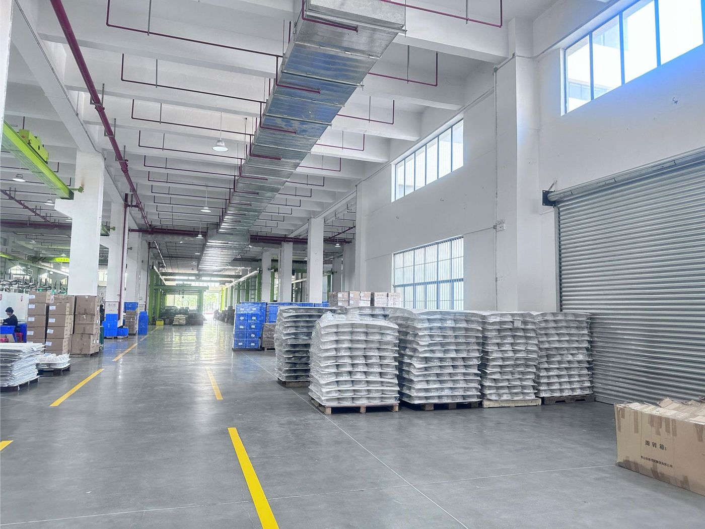 Palletised, bagged finished goods staged in the on-site warehouse beside a roller-shutter loading door
