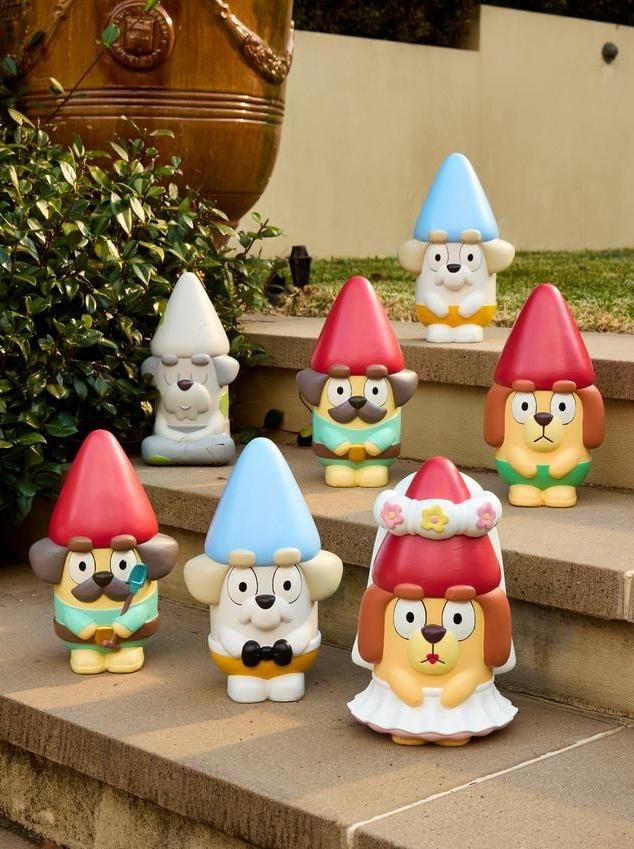 Seven Bluey character garden gnome statues from the licensed range staged on outdoor garden steps